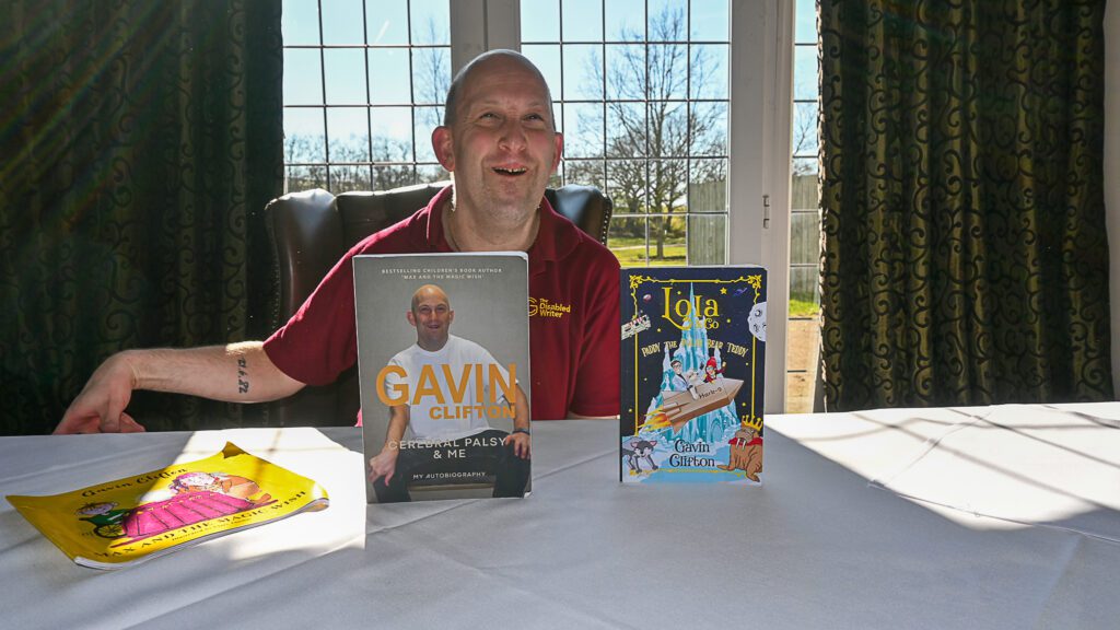 Author Gavin Clifton, sits in front of a colelction of his books
