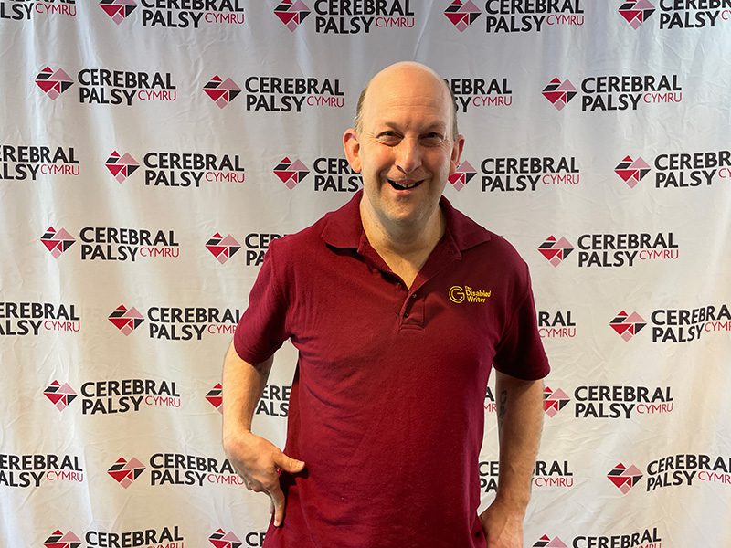Gavin Clifton, Author, standing next to a banner for Cerebral Palsey Cymru