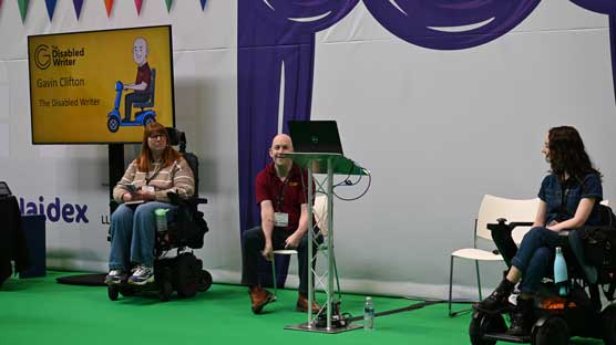 Gavin Clifton is on stage with other speakers, delivering a speech at Naidex 2026